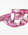Inflatable pink and white tropical leaf print pool hammock with mesh center and three cushioned supports.