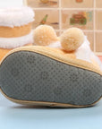 Close-up of a plush toy resembling a cake with a textured gray sole on a light blue surface.