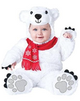 A baby wearing a white plush polar bear costume with a red scarf featuring white snowflakes, black paw pads, and a bear face hood on a plain white background.