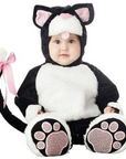 A baby wearing a black and white cat costume with pink accents, including a hood with cat ears, a pink nose, and a long tail with a pink bow. The costume includes paw-print covered feet.