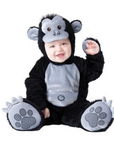 A baby wearing a plush gorilla costume, sitting against a plain white background. The costume is black with a gray belly panel, gray ears, and gray paw pads with white claw details.