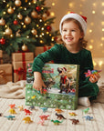 A young child wearing a Santa hat sits on a blanket in front of a decorated Christmas tree, holding a Christmas advent box labeled 'Dino Advent' with small colorful dinosaur toys scattered around on a beige rug.