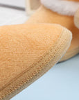Close-up of a tan slipper with a soft texture on a light blue background