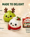 Two cute dumpling-shaped holiday gift boxes with cartoon faces are shown on a warm beige background with text callouts and the retail box. The front dumpling is white with a red scarf, and the back dumpling is light green with brown antlers.