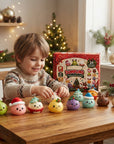 A child sits at a wooden table with a set of small, cute, pastel-colored squishy toys shaped like holiday characters, with their red and white 'DUMPING' brand box standing behind them in a cozy, decorated Christmas room.