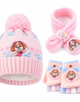 A children's winter hat, scarf, and fingerless glove set in pink, featuring a cartoon dog character patch on each item and pastel paw-print details on the hat.